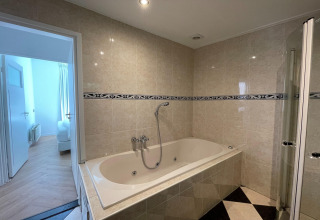 Badeværelse i Wellness Suite-lodge i Holland med badekar, bruser og flisevægge.