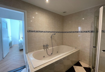 Baño en la lodge Wellness Suite en los Países Bajos con bañera, ducha y paredes de azulejos.