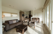 Bright modern living area with sofa, armchairs and kitchen at Holiday park Boomhiemke 7 in Netherlands.