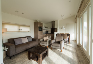Bright modern living area with sofa, armchairs and kitchen at Holiday park Boomhiemke 7 in Netherlands.