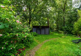 En fredelig have med blomstrende buske, grøn græsplæne og et skur, taget ved Wellnes suite i Holland.