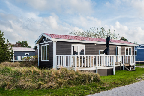 Ferienhaus im Holiday Park Boomhiemke 6 mit Terrasse und Garten, umgeben von Natur und blauem Himmel.