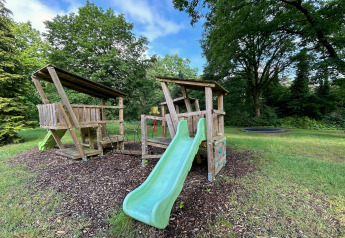 Zona de juegos con estructura de madera, tobogán y rocódromo en el lodge Wellness Suite en Países Bajos.