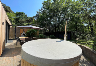 Udendørs terrasse ved Wellnes suite lodge i Holland med spisebord, parasol, pejs og overdækket spabad.
