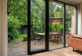 View from living room to patio with dining table, chairs, and umbrella at Wellnes suite in the Netherlands.