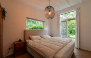 Slaapkamer van de Forest suite lodge in Nederland met groot bed, houten meubels en uitzicht op het bos.