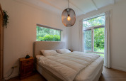Dormitorio en la Forest suite lodge en los Países Bajos con cama grande, muebles de madera y vista al bosque.