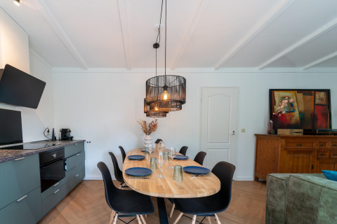 Eetkamer en keuken in Forest Suite, Nederland, modern interieur met ovale tafel en houten dressoir.