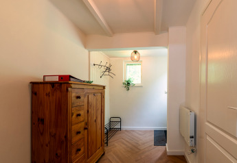 Entrance of Forest suite lodge in the Netherlands with wooden cabinet, coat rack, and small window.