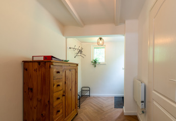 Entrance of Forest suite lodge in the Netherlands with wooden cabinet, coat rack, and small window.