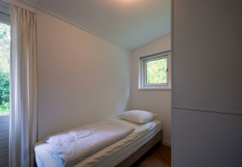 Lichte eenpersoonskamer in Forest suite lodge, Nederland, eenpersoonsbed en uitzicht op natuur.