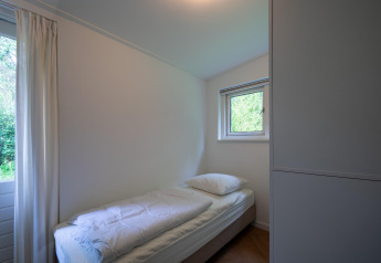 Lichte single kamer in Forest suite lodge, Nederland, met bed en raam naar de natuur.