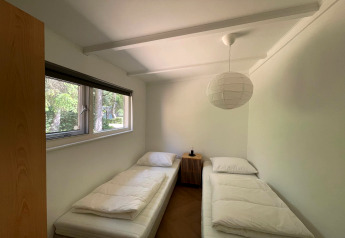 Lichte kamer in Forest Suite, Nederland, twee eenpersoonsbedden en een raam met uitzicht op het bos.