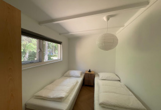 Helles Zimmer im Forest Suite, Niederlande, mit zwei Einzelbetten, Fenster und Waldblick.