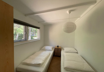 Bright room at Forest Suite in the Netherlands, two single beds, window view of the forest outside.