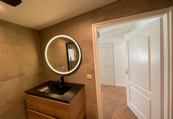 Modern bathroom at Forest Suite in the Netherlands, featuring a round mirror and wood sink cabinet.