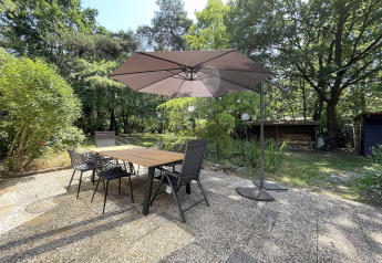 Buitenterras met tafel, stoelen en parasol bij Forest suite lodge in Nederland, omgeven door groen.