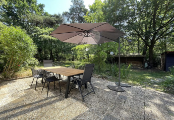Terraza exterior en la Forest suite de Países Bajos, con mesa, sillas, sombrilla y vegetación densa.