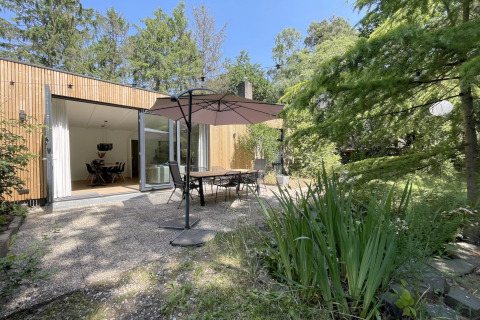 Terrasse extérieure de la Forest suite aux Pays-Bas, table à manger, parasol et verdure luxuriante.