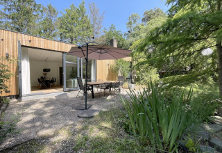 Terrasse extérieure de la Forest suite aux Pays-Bas, table à manger, parasol et verdure luxuriante.