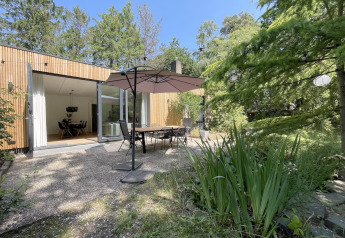 Outdoor patio at Forest suite lodge in the Netherlands with dining set, umbrella, and lush greenery.