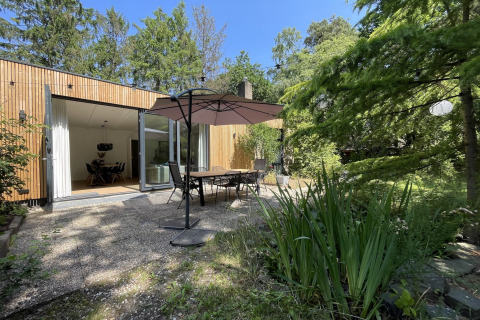 Outdoor patio at Forest suite lodge in the Netherlands with dining set, umbrella, and lush greenery.