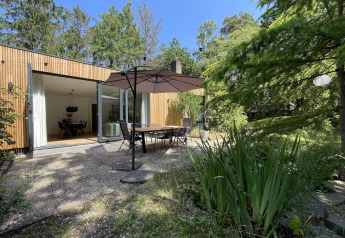 Buitenterras bij Forest suite lodge in Nederland met tafel, stoelen, parasol en omringend groen.