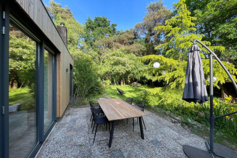 Patio view at Forest Suite lodge in the Netherlands with dining table, chairs, and lush green garden.