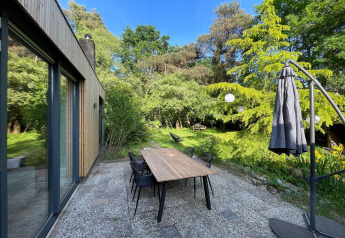 Terraszicht bij Forest Suite-lodge in Nederland met tuinset, stoelen en groene, bosrijke omgeving.