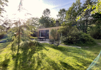 Zonnig exterieur van Forest suite lodge in Nederland, omgeven door groen en bomen, rustgevende sfeer.
