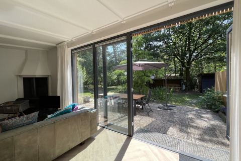 Living room of the Forest suite lodge in the Netherlands with sliding doors opening to a patio garden.