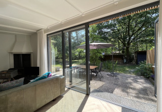 Woonkamer in Forest suite lodge Nederland, schuifdeur naar terras en bosrijke tuin.