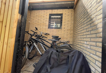 Fietsen geparkeerd in een klein hokje bij Forest Suite, Nederland, met een zwarte tas op de voorgrond.