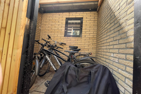 Fietsen staan tegen een bakstenen muur bij Forest Suite, Nederland, met zwarte tas op de voorgrond.