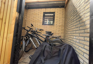 Bicycles parked in a sheltered corner by a brick wall at Forest Suite lodge in the Netherlands, black bag front.