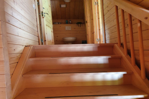 Wooden staircase leads up to a bathroom with toilet in a cozy chalet at Casa Madeira, Netherlands.