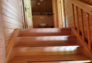 Wooden staircase leads up to a bathroom with toilet in a cozy chalet at Casa Madeira, Netherlands.