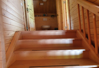 Wooden staircase leads up to a bathroom with toilet in a cozy chalet at Casa Madeira, Netherlands.