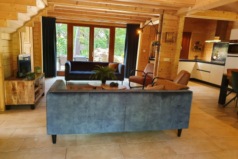 Salon au décor bois, canapés modernes et grandes fenêtres à la villa forestière Casa Madeira, Pays-Bas.