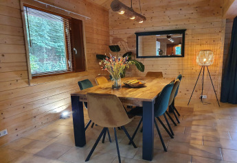 Eetkamer in luxe bosvilla Casa Madeira in Nederland met houten muren, grote tafel en warme verlichting.