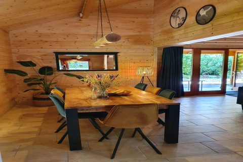 Essbereich in der Luxus-Waldvilla Casa Madeira mit Holzwänden, modernen Möbeln und Blick ins Grüne.