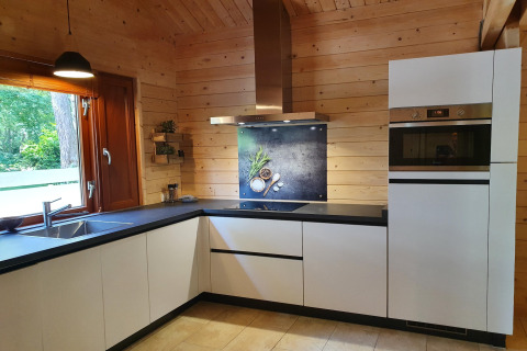 Modern white kitchen with wood walls and built-in appliances in the 6-person Casa Madeira chalet, Netherlands.