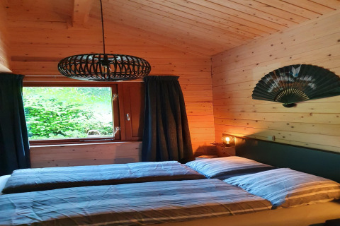 Dormitorio acogedor de la villa Casa Madeira, Países Bajos, con paredes de madera, cama doble y abanico asiático.