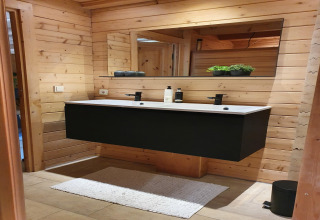 Moderne badkamer met zwart dubbel wastafelmeubel en houten wand in Casa Madeira, Nederland.
