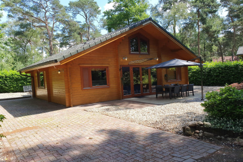 Luxe bosvilla Casa Madeira voor 6 personen met houten gevel, terras, tuinset en grote parasol.