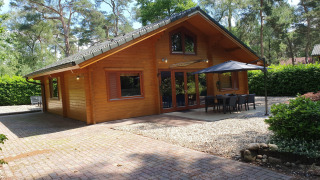 Chalet de lujo Casa Madeira en el bosque para 6 personas, con terraza, parasol y comedor exterior.
