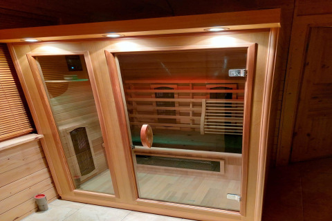 Luxury infrared sauna with glass door and wood frame, lit from above, at Casa Madeira forest villa, Netherlands.