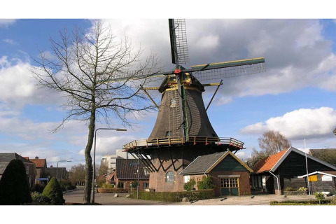 Photo d'un moulin à vent néerlandais traditionnel dans un hébergement glamping entouré de chalets.
