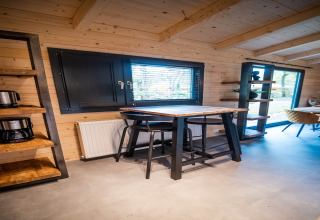 Interior de la lodge de bienestar para 4 personas en Países Bajos con muebles modernos y ventanales grandes.