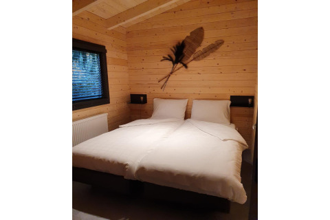 Slaapkamer van een 4-persoons wellness lodge in Nederland met houten muren en twee aparte bedden.